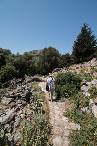 Man walking on rocks against clear sky