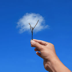 Low angle view of person hand holding blue sky