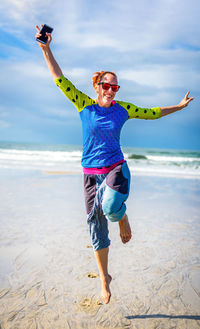 Portrait of woman jumping at beach