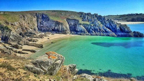 Scenic view of sea and rocks against blue sky