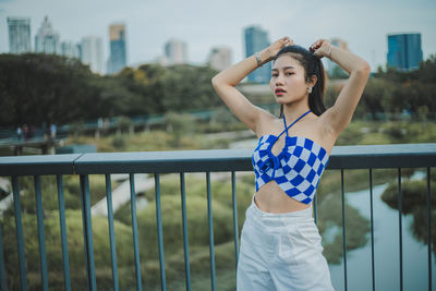 Young woman standing against railing