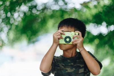 Boy playing with toy camera at park