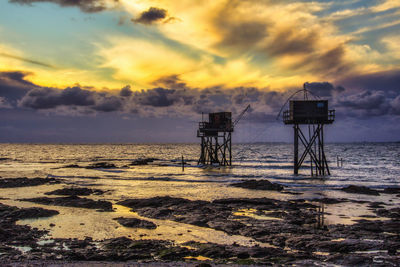Lifeguard hut on beach against sky during sunset