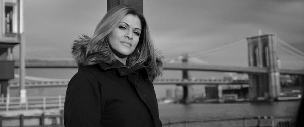 Portrait of beautiful young woman in city against sky