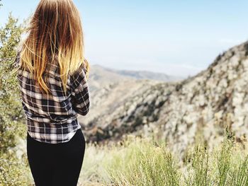 Rear view of woman with blond hair standing on mountain