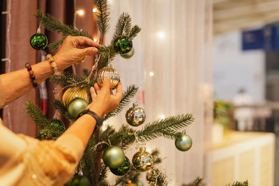 Senior woman decorating a christmas tree at home.