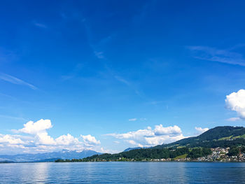 Scenic view of sea and mountains against blue sky