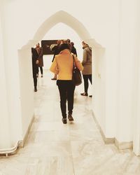 Rear view of people walking in corridor of building