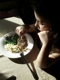 High angle view of girl eating meal with sunlight on food