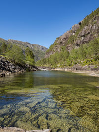 Scenic view of lake and mountains against clear blue sky