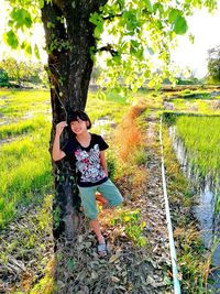 Full length of young woman standing against trees