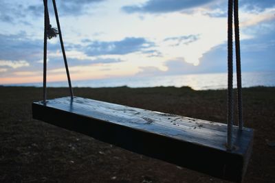 Empty swing in playground against sky