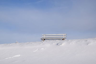 Lifeguard hut on snow covered land against sky