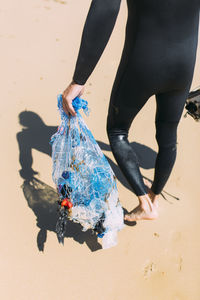 Male volunteer holding mesh bag on sunny day