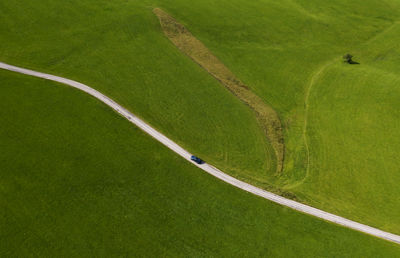 Austria, upper austria, hausruckviertel, drone view of car driving along dirt road cutting through green field