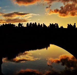 Silhouette trees by lake against sky during sunset