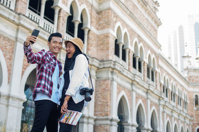 Low angle view of people standing in front of buildings