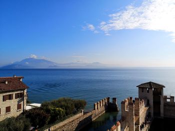 Buildings by sea against sky