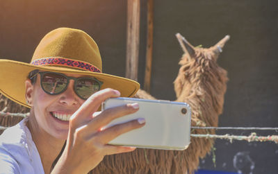 Young tourist takes selfies of alpacas and llamas on the farm. farming industry in peru. 