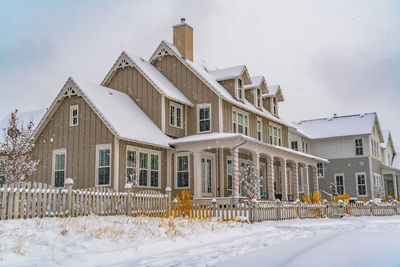 Snow covered houses by buildings against sky