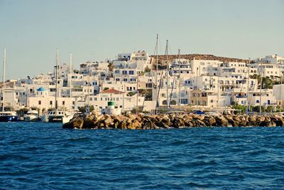 Buildings by sea against clear sky