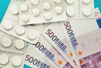 Money pills. medicine pills on euro bills on a blue background. covid-19 coronavirus pills are in