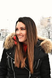 Portrait of smiling young woman standing in snow