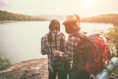 Friends standing by lake against sky