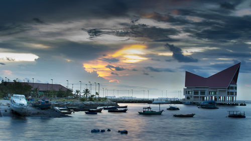 Boats moored in harbor at sunset