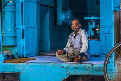 Portrait of man sitting against blue wall