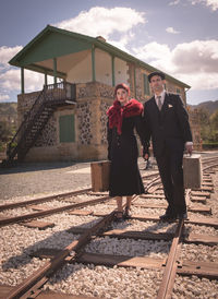 Woman standing by railroad tracks against sky