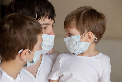 Father and sons in medical masks at home. image with selective focus
