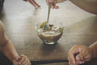 Cropped hand picking food with spoon from bowl on table