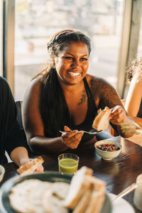 Smiling woman eating breakfast sitting at dining table in retreat center