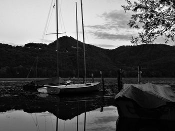 Boats moored in calm lake against mountain range