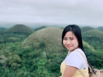 Portrait of smiling woman against landscape