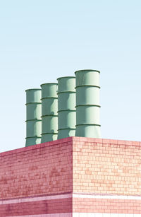 Low angle view of smoke stacks on building against clear sky