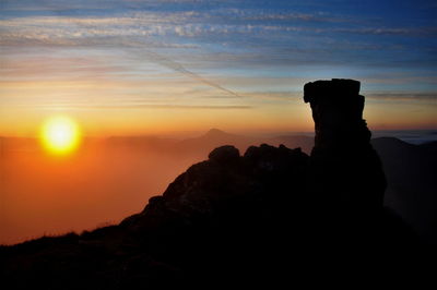 Silhouette rock against sky during sunset