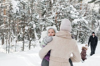 Dad and mom and daughters have fun in the snowy forest. high quality photo