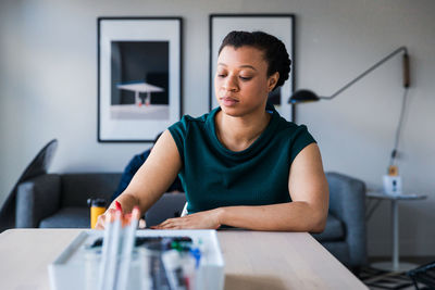 Confident businesswoman writing on document at table in office