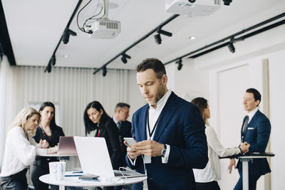 Businessman working over phone while standing in office seminar