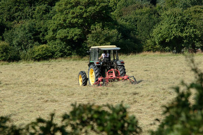 Tractor on field against trees