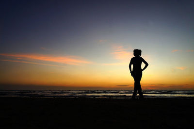 Silhouette man standing on beach against sky during sunset