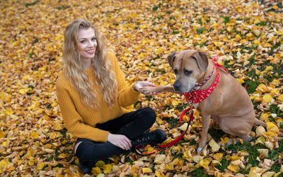 Woman with dog sitting on autumn leaves