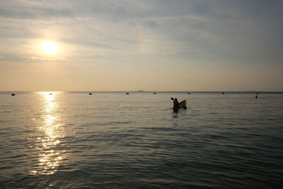 Silhouette people standing on sea against sky during sunset