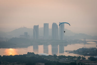 Parachute flying above river in foggy weather during sunrise