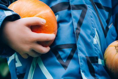 The child holds an orange pumpkin in his hands. halloween and thanksgiving season. harvesting