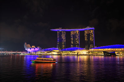 Illuminated bridge over river in city at night