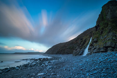 Scenic view of sea and mountains against blue sky