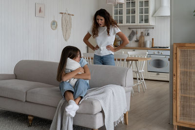 Young woman using mobile phone while sitting on sofa at home